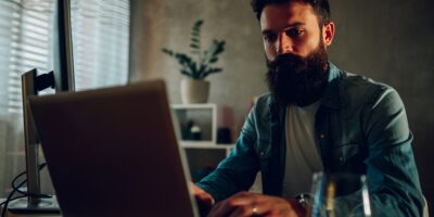A smart software engineer is sitting in his darkened home office and developing software.